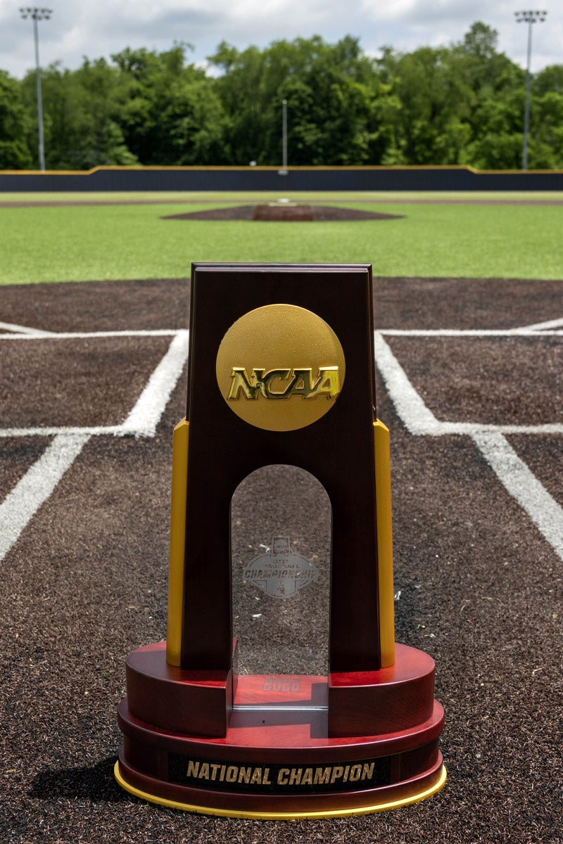 An NCAA championship trophy sitting at home plate on a baseball field.