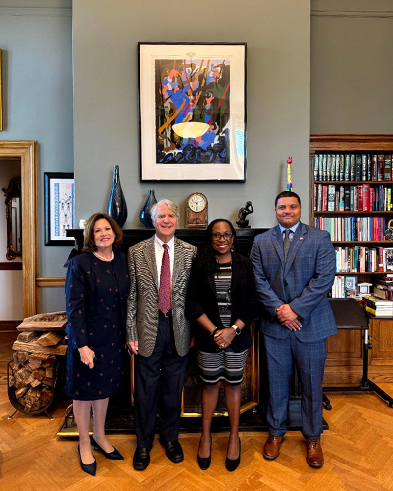 Four people in business wear standing in a congressional office.
