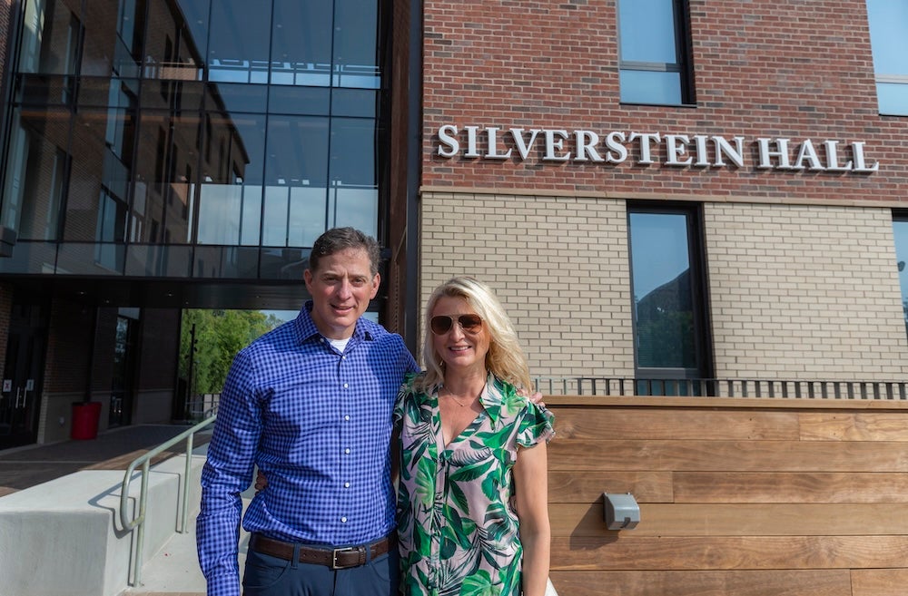 The Silversteins stand in front of Silverstein Hall on campus