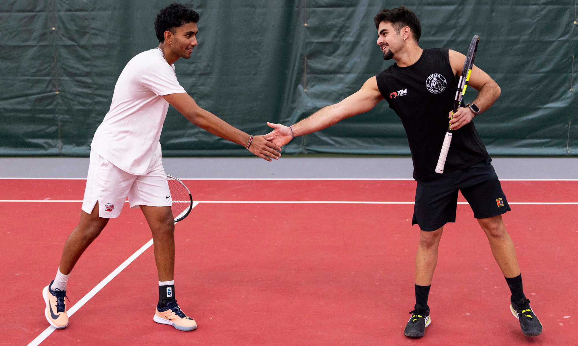 Two tennis players shake hands on the court.