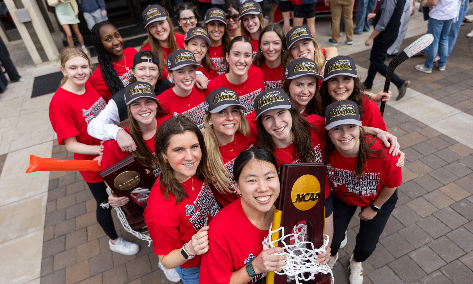 Abby Cooch with her teammates holding their NCAA championship trophy and net from their championship basketball game.