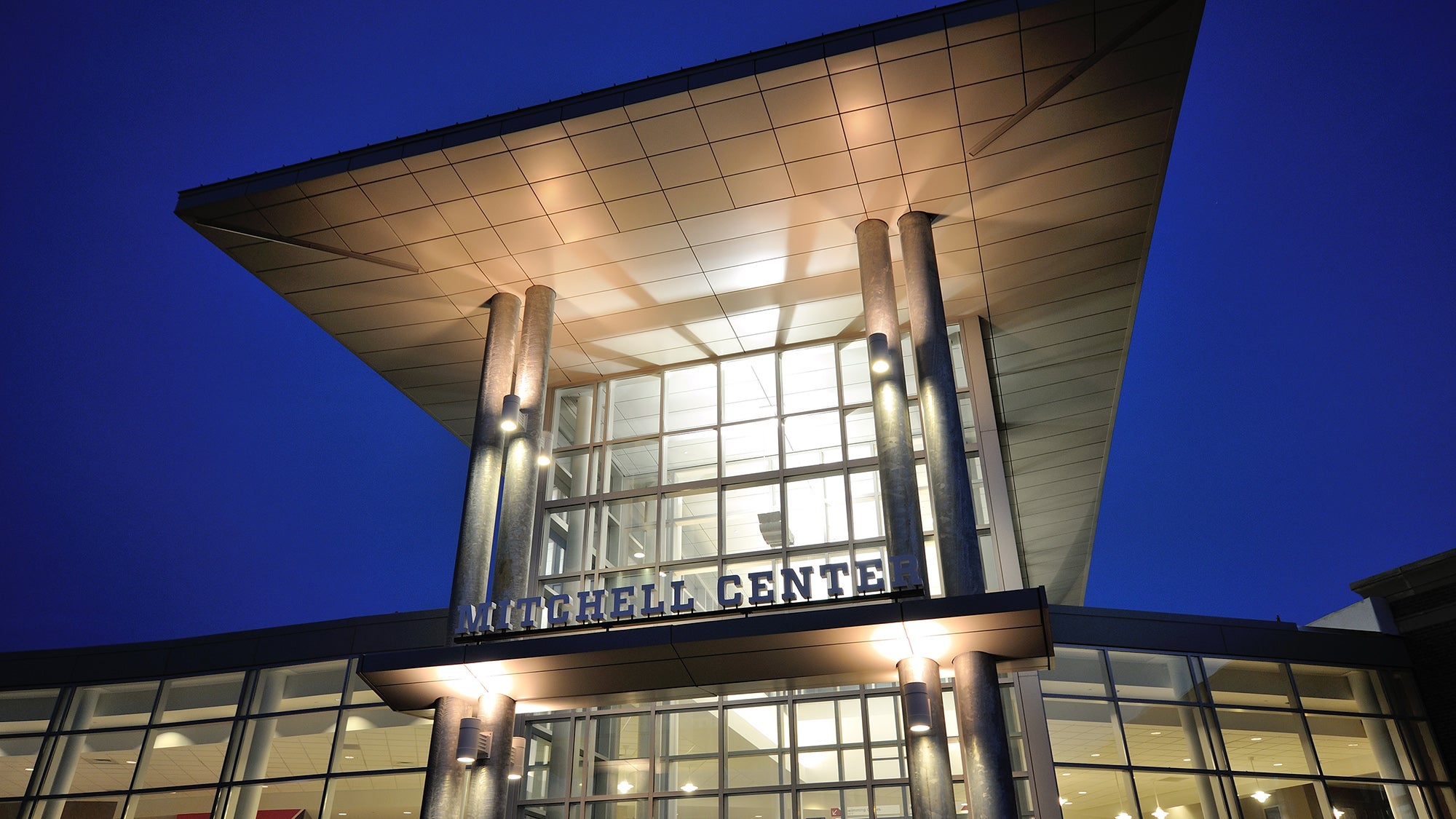 The front of the Mitchell Center is lit up by lights.