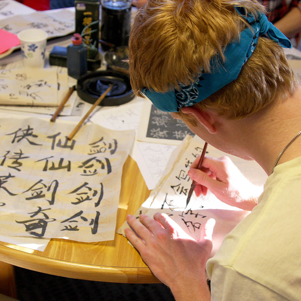 Picture of a student writing Chinese with a brush and ink.