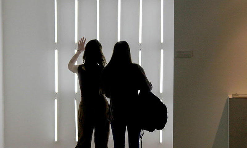 Two figures standing in front of strips of light