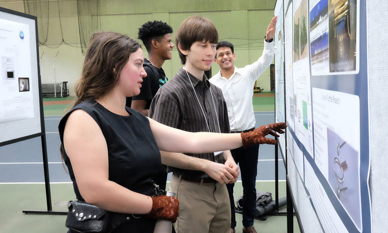 Students pointing at research posters