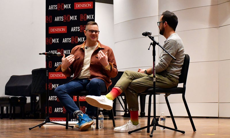 Photo of a ReMix discussion event; two men sitting in front of microphones talking on a stage.