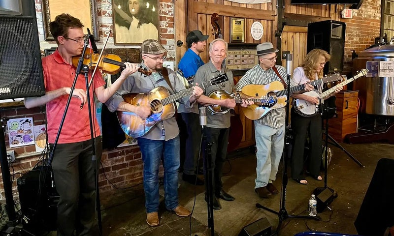 A bluegrass band with Rich Baker center lined up on a small stage.