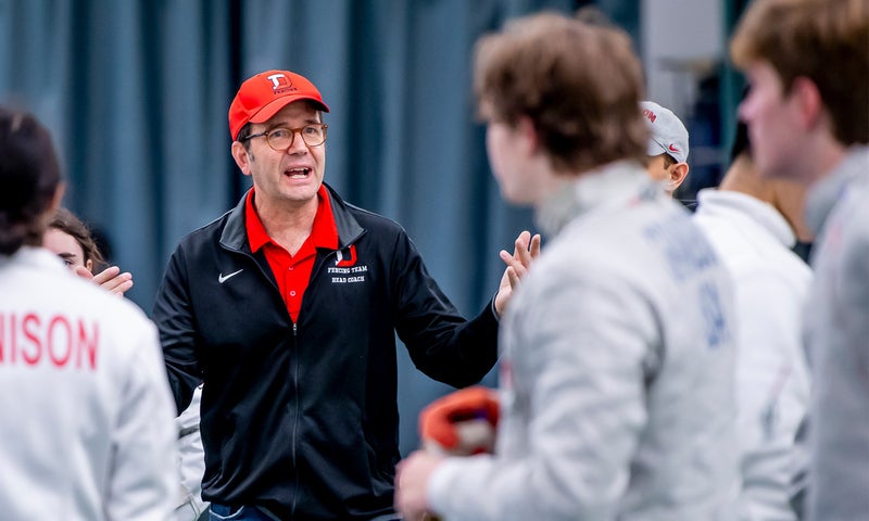 Fencing coach Peter Grandbois with several fencers in uniform.
