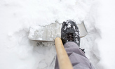 Foot pressing down on shovel in snow