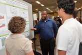 Students and professor discussing a research poster