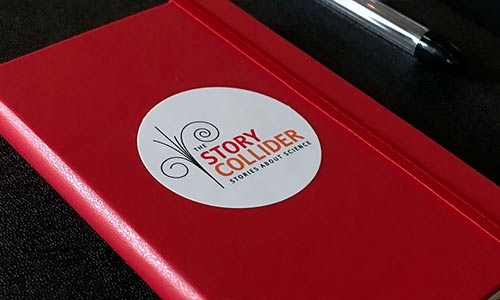 Photo of a red notebook that says "The Story Collider" on it
