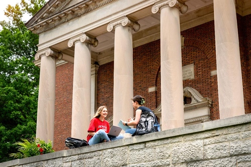 Students sit on a wall in front of Swasey Chapel