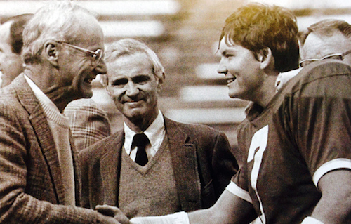 In the fall of 1987 on Deeds Field, senior Grant Jones '88 shakes hands with Denison  Board Chair Chuck Brickman ''54 as University President Andrew DeRocco looks on.