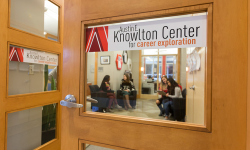 Sign on the door that says 'Austin E. Knowlton Center for Career Exploration with people sitting in the background