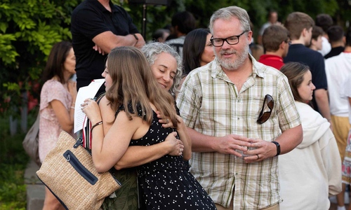 A student hugging parents as they say goodbye on a college campus