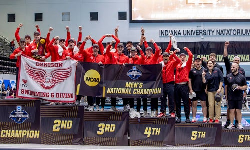 The Denison swimming and diving team celebrates on the podium poolside after winning the national championship.