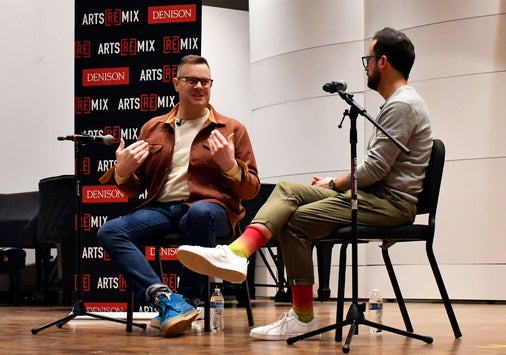 Photo of a ReMix discussion event; two men sitting in front of microphones talking on a stage.