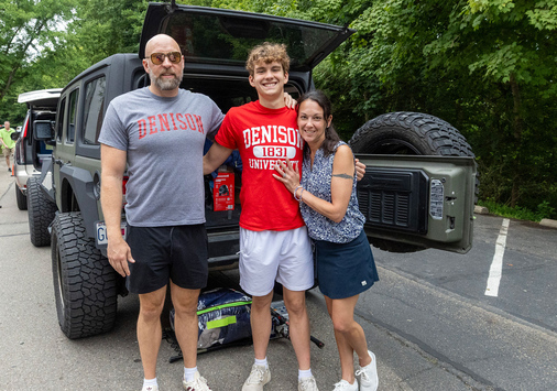 A famiily standing in behind a vehicle with an open door
