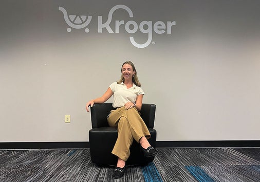 Photo of Jordyn Maurer ’26 sitting in a chair under the Kroger logo.