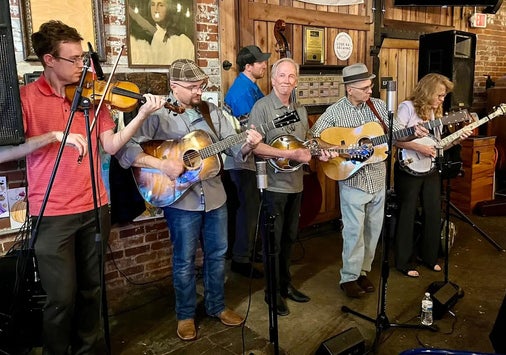 A bluegrass band with Rich Baker center lined up on a small stage.