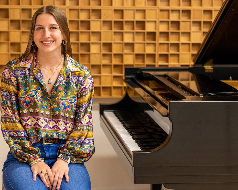 Ellie Blasko '23 sitting next to a piano