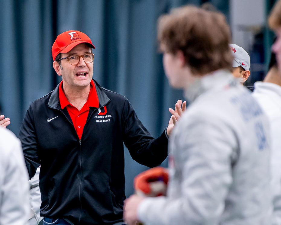 Fencing coach Peter Grandbois with several fencers in uniform.