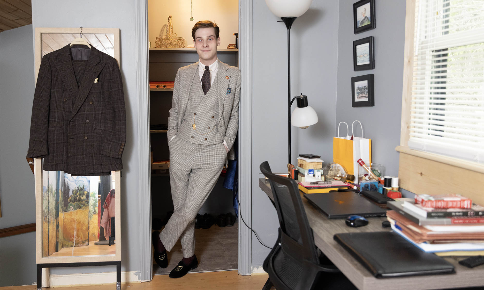 Sam Cuyler leaning against a door frame wearing a three-piece suit.