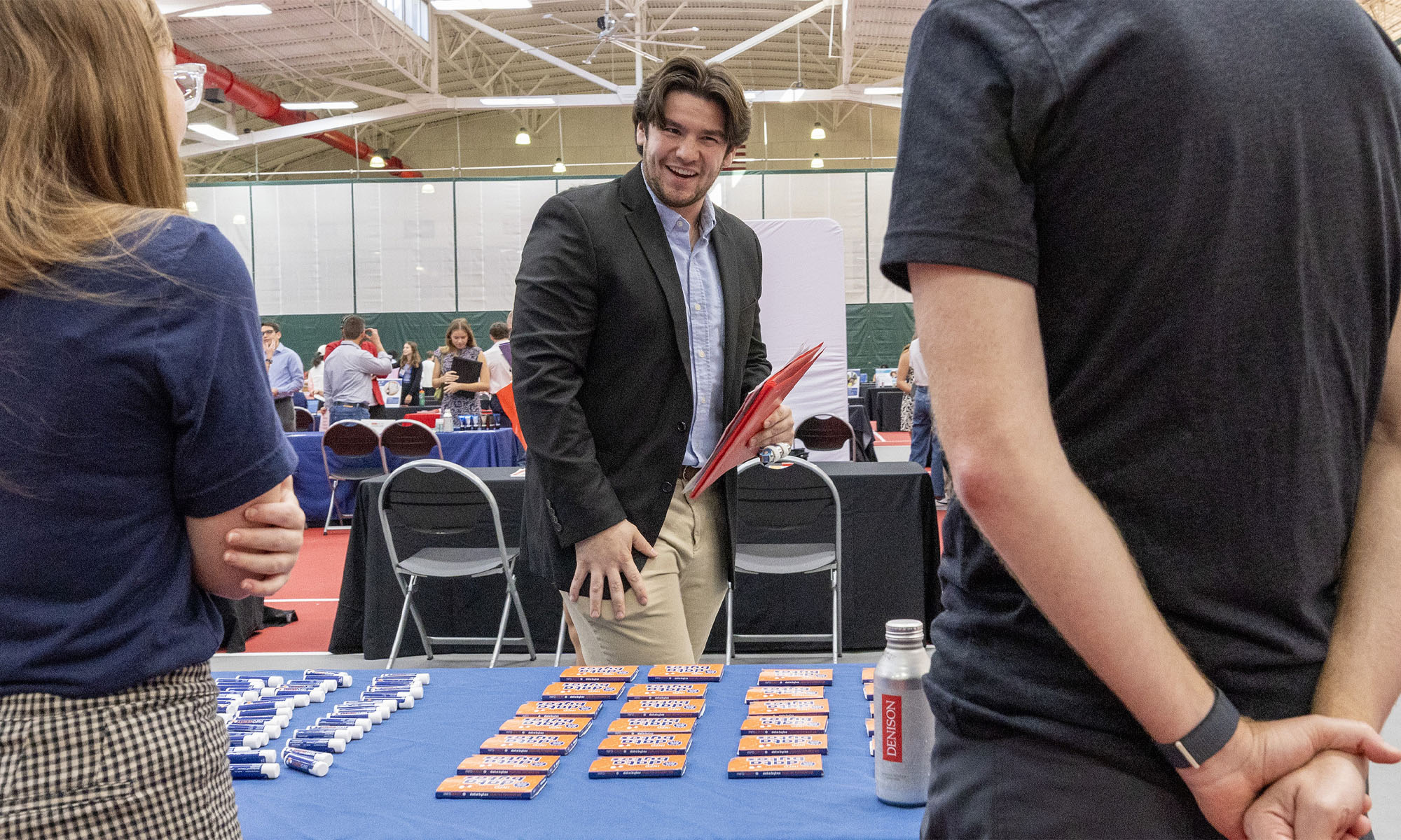 A student in a suit approaches a table to talk with company reps.