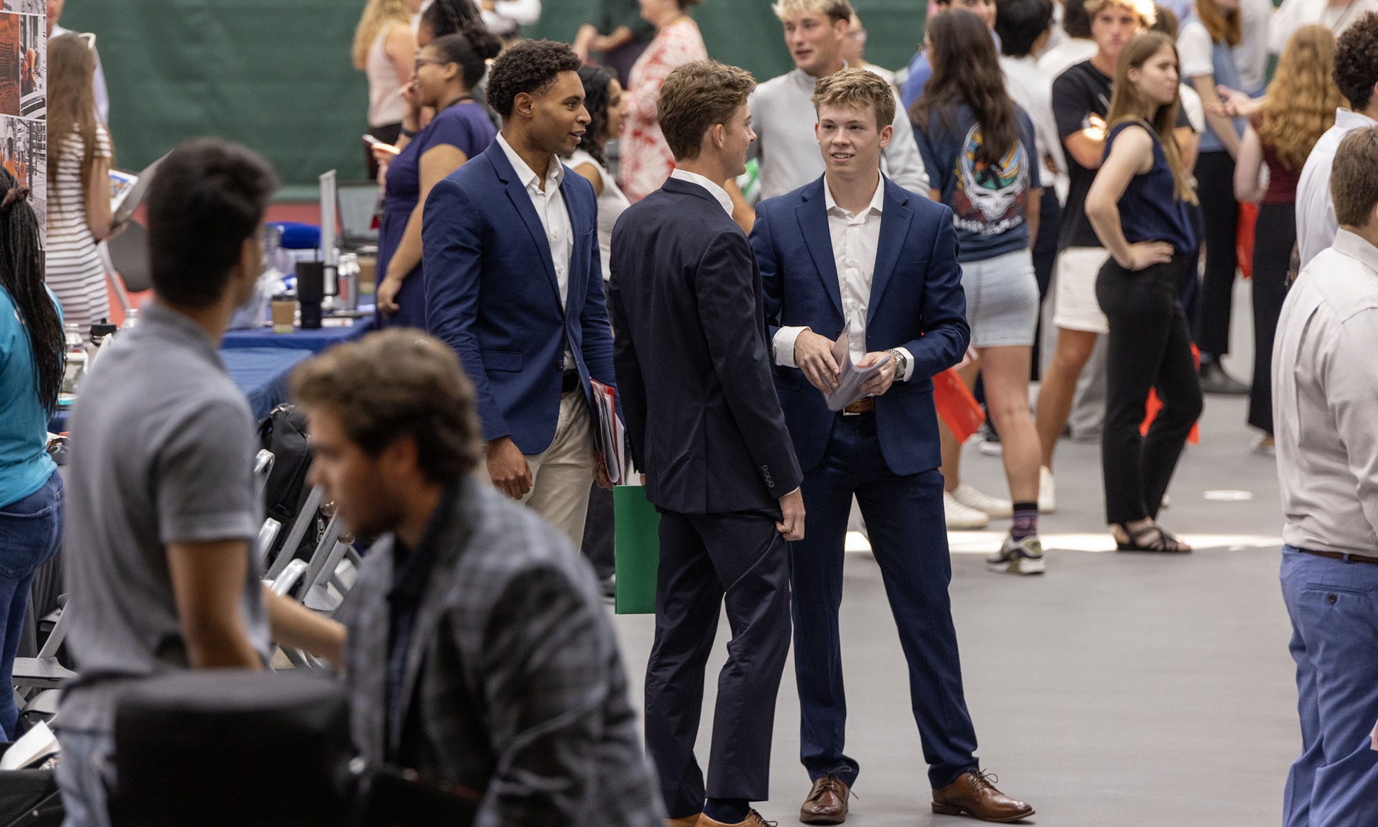A group of students wearing suits stand in the center of the Career Expo.