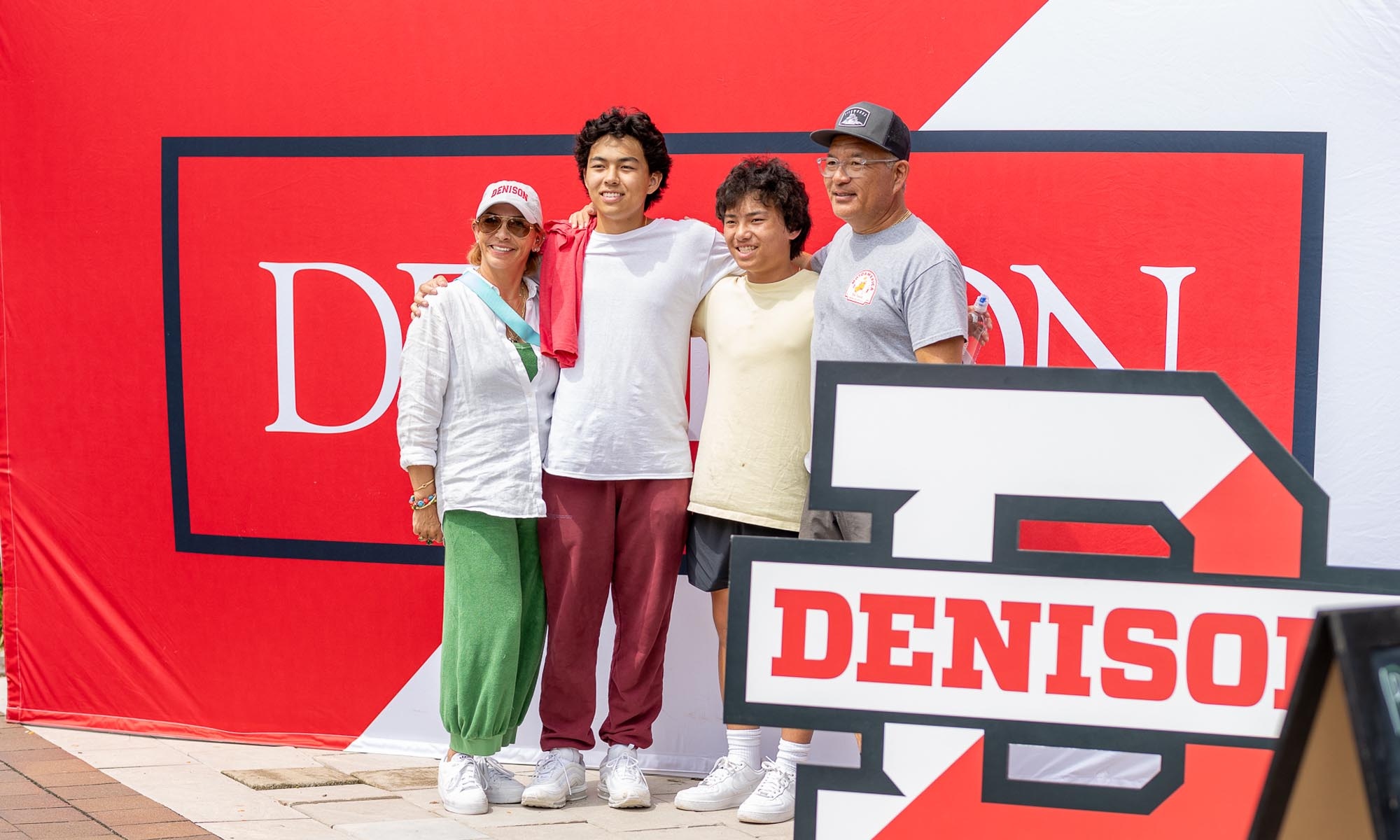 A student and family posing in front of a Denison wall banner.