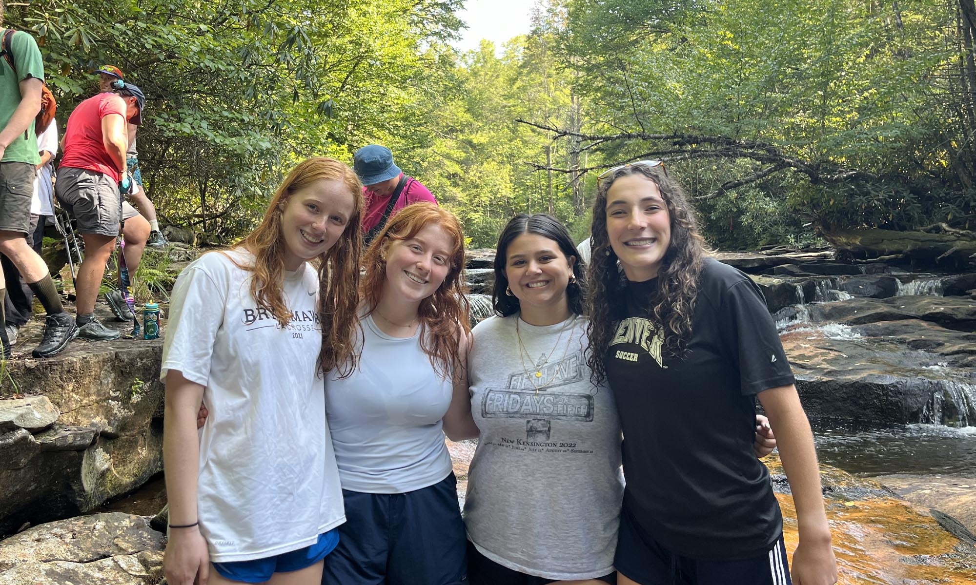 Four friends pose for a picture while hiking through a small creek.
