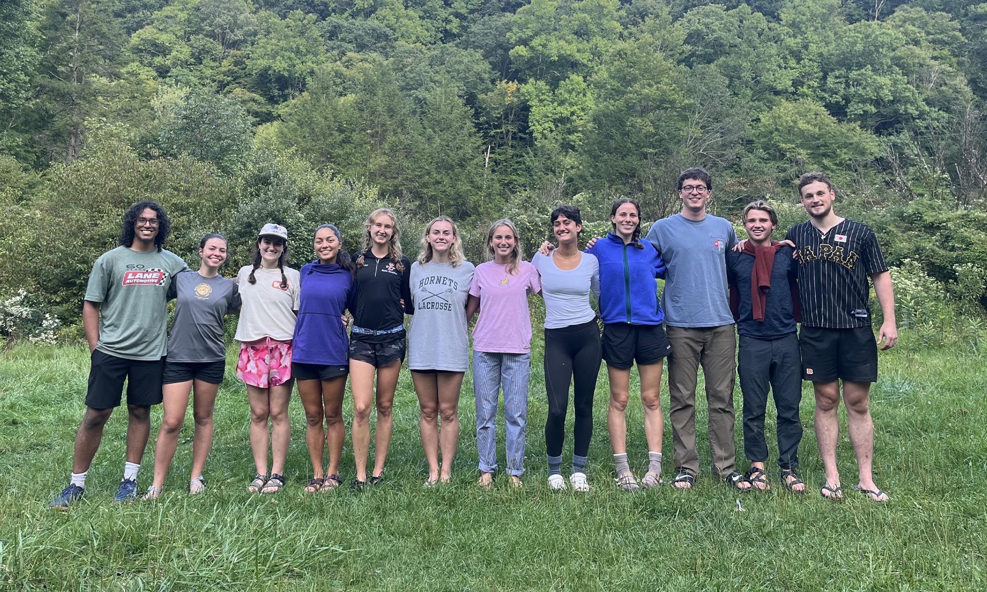 A large group of first-year students pose for a photo in a field.