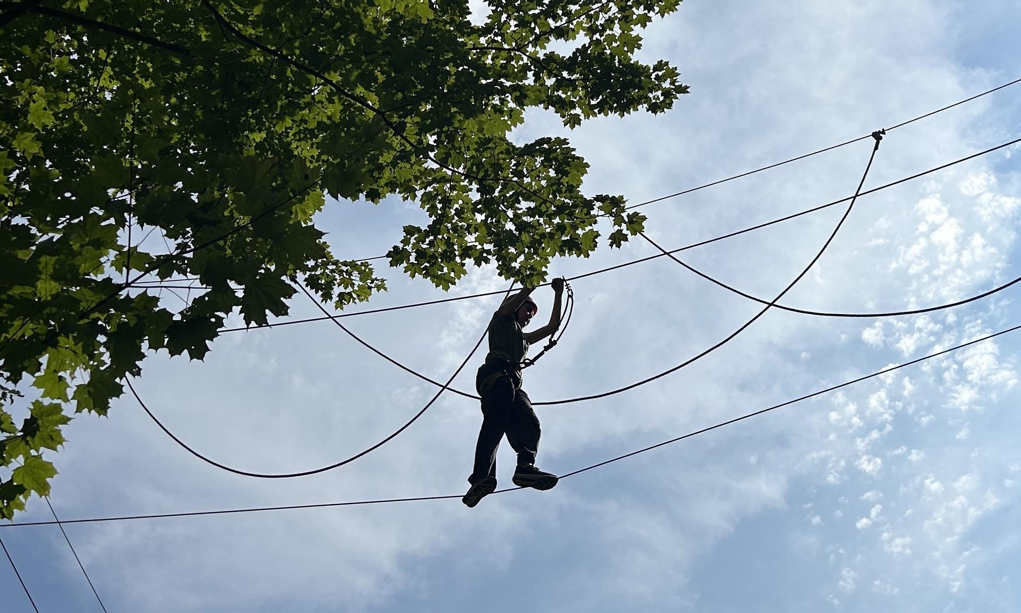 A student completing a ropes course high in the trees.