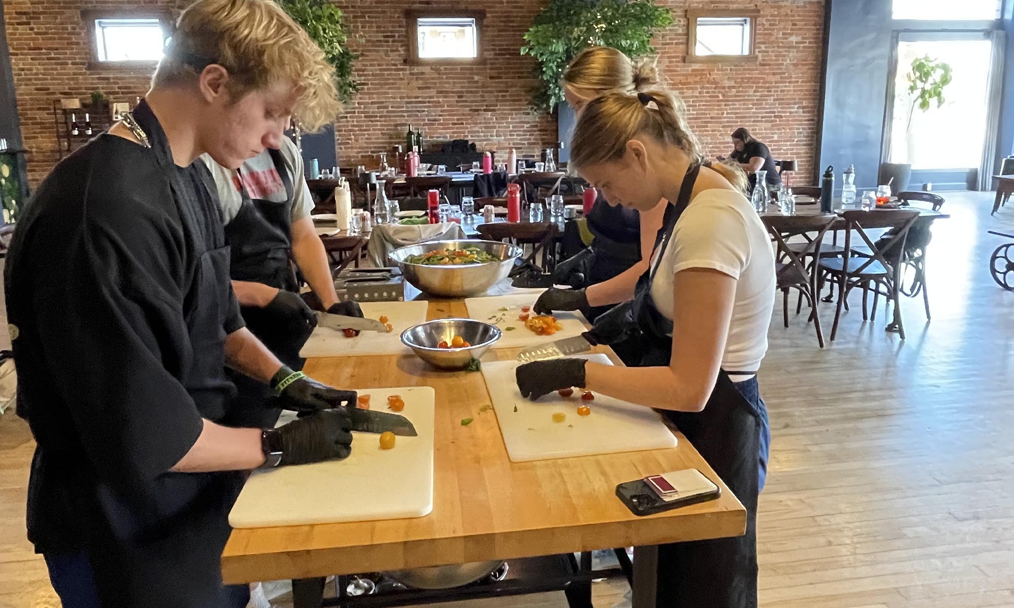 Students in a training kitchen learn how to chop and slice vegetables.
