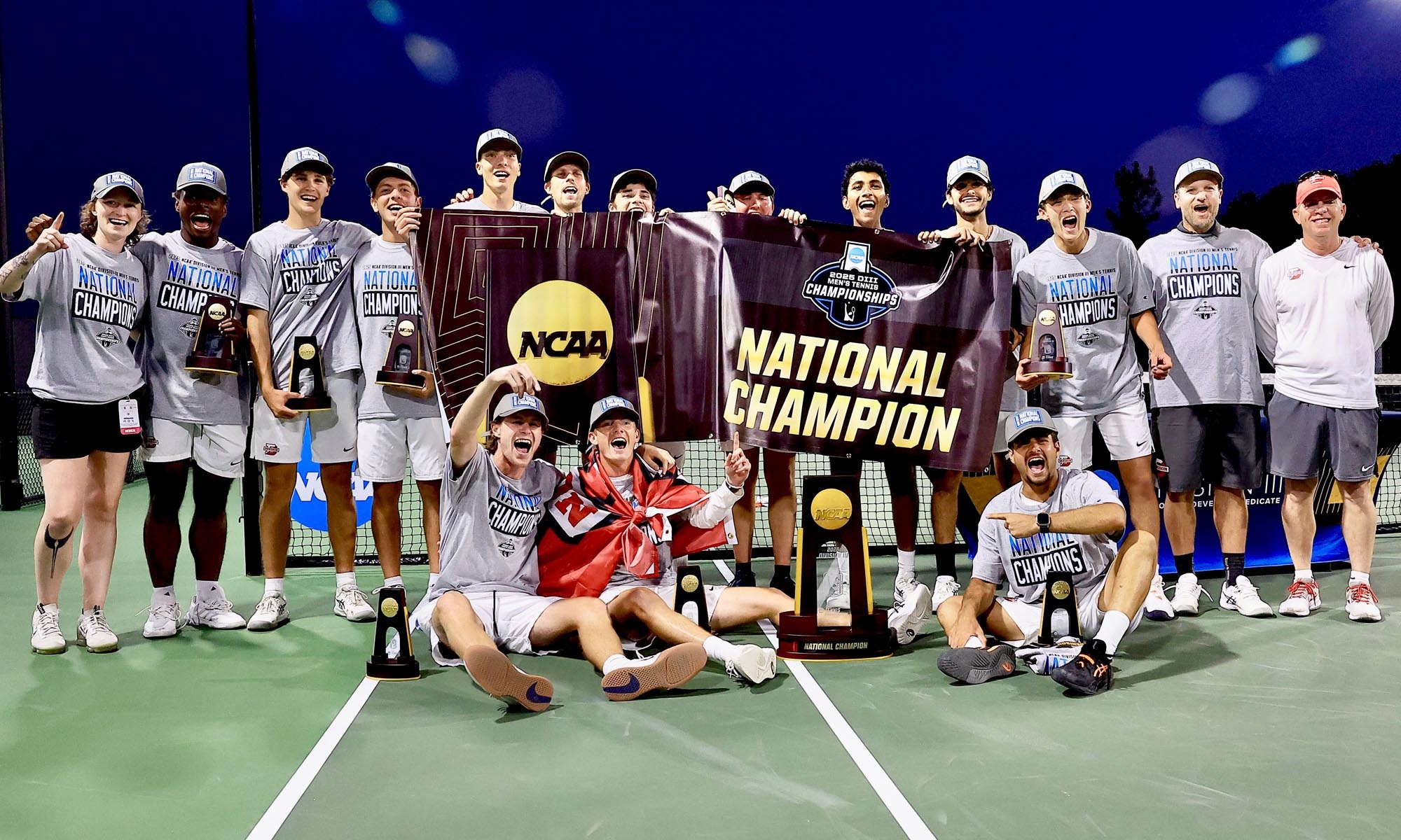 The Men's Tennis team poses on the court with their National Championship trophy.