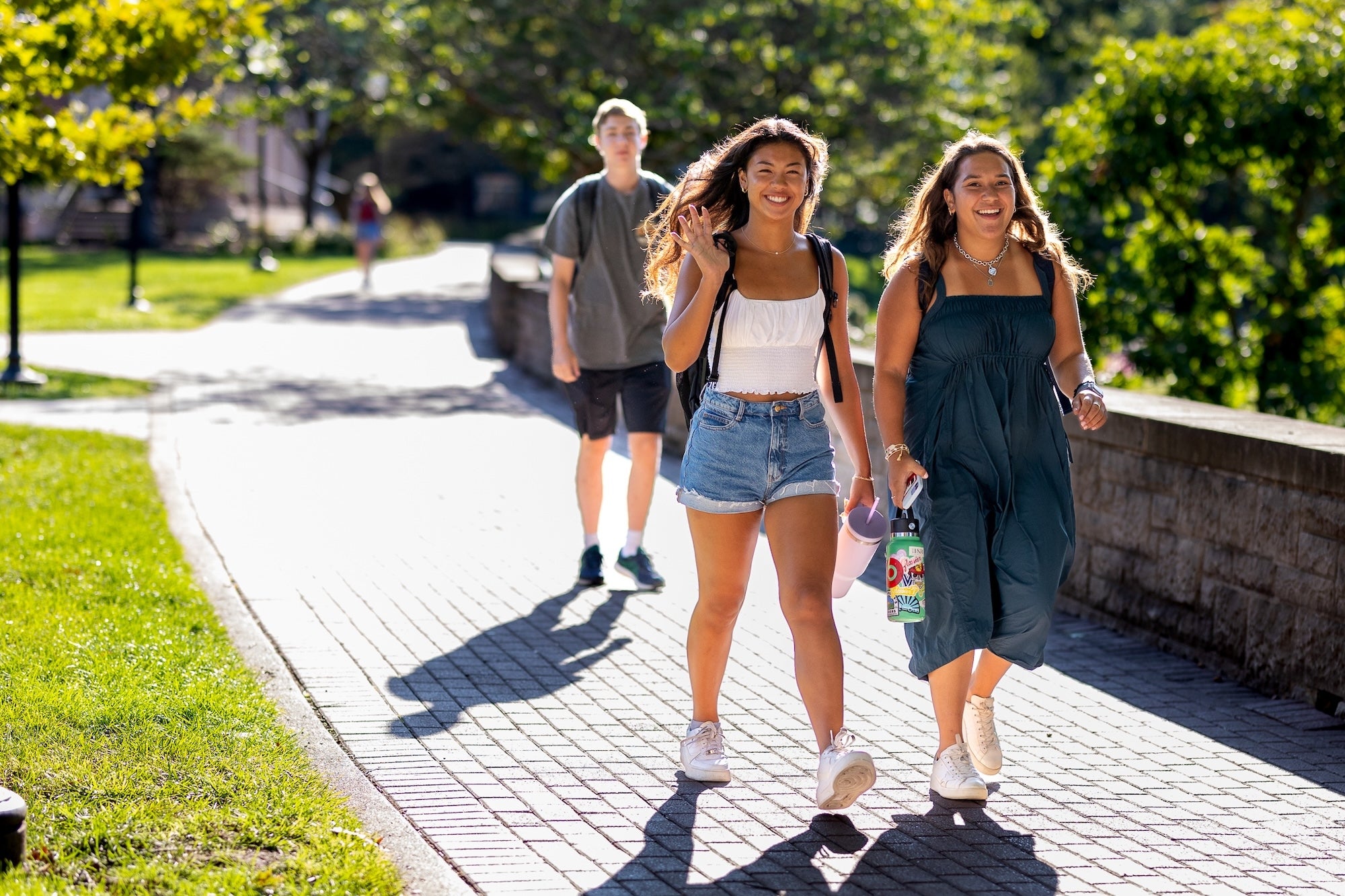 Students smiling and waving as they walk to class