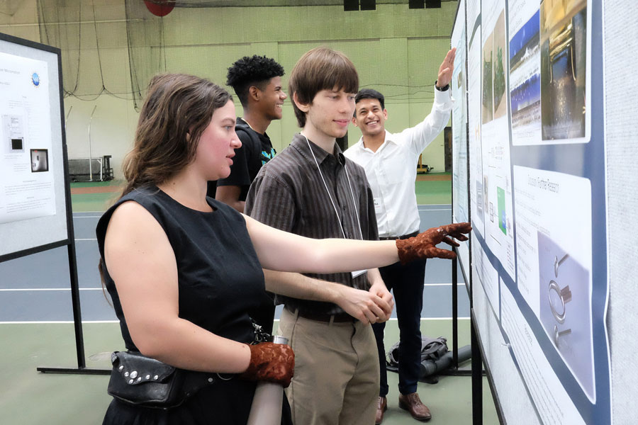 Students pointing at research posters