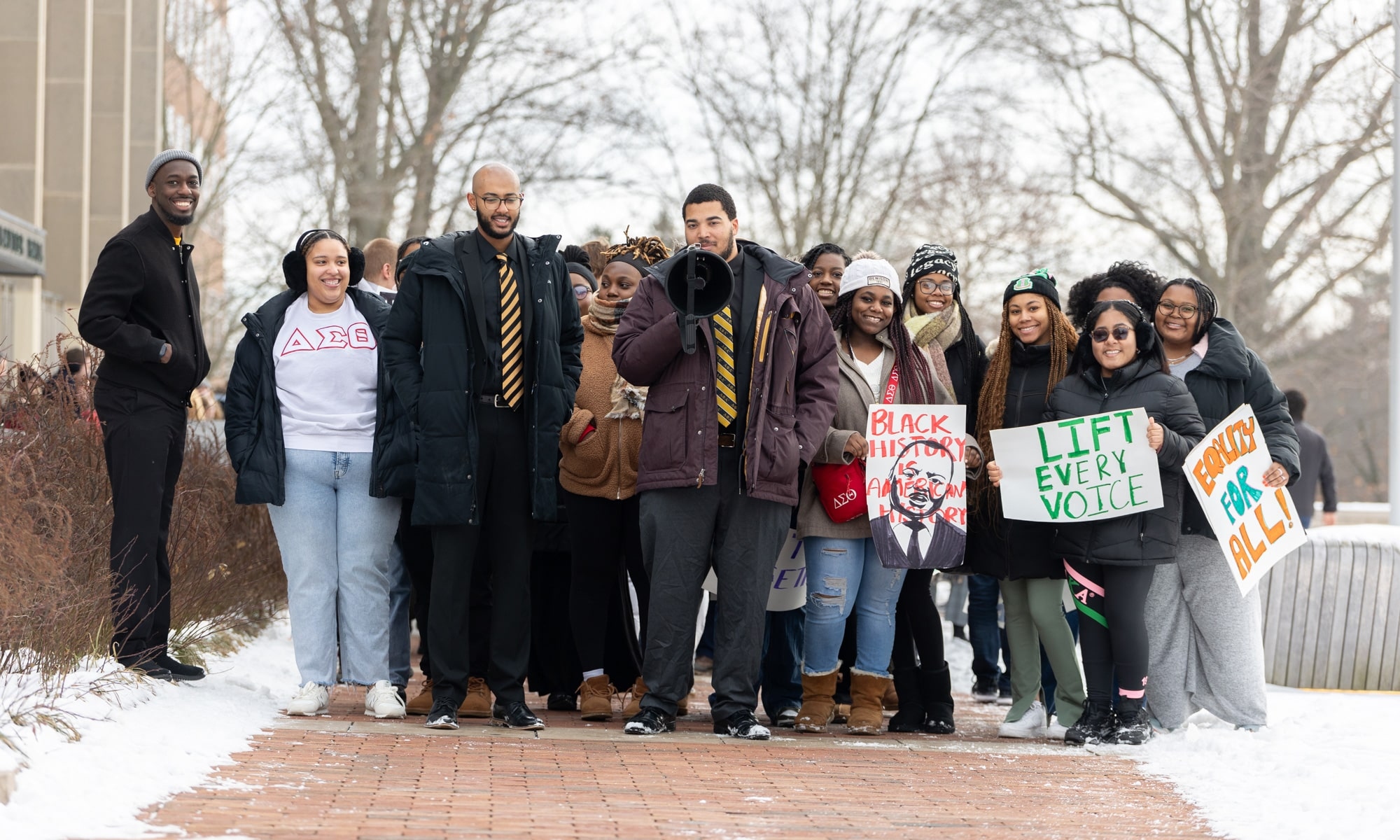 Tewoflos Tewoldeberhan ’25 and Thomas Coffey ’25, both wearing ties, lead the march from Slayter Hall to Mitchell Center.