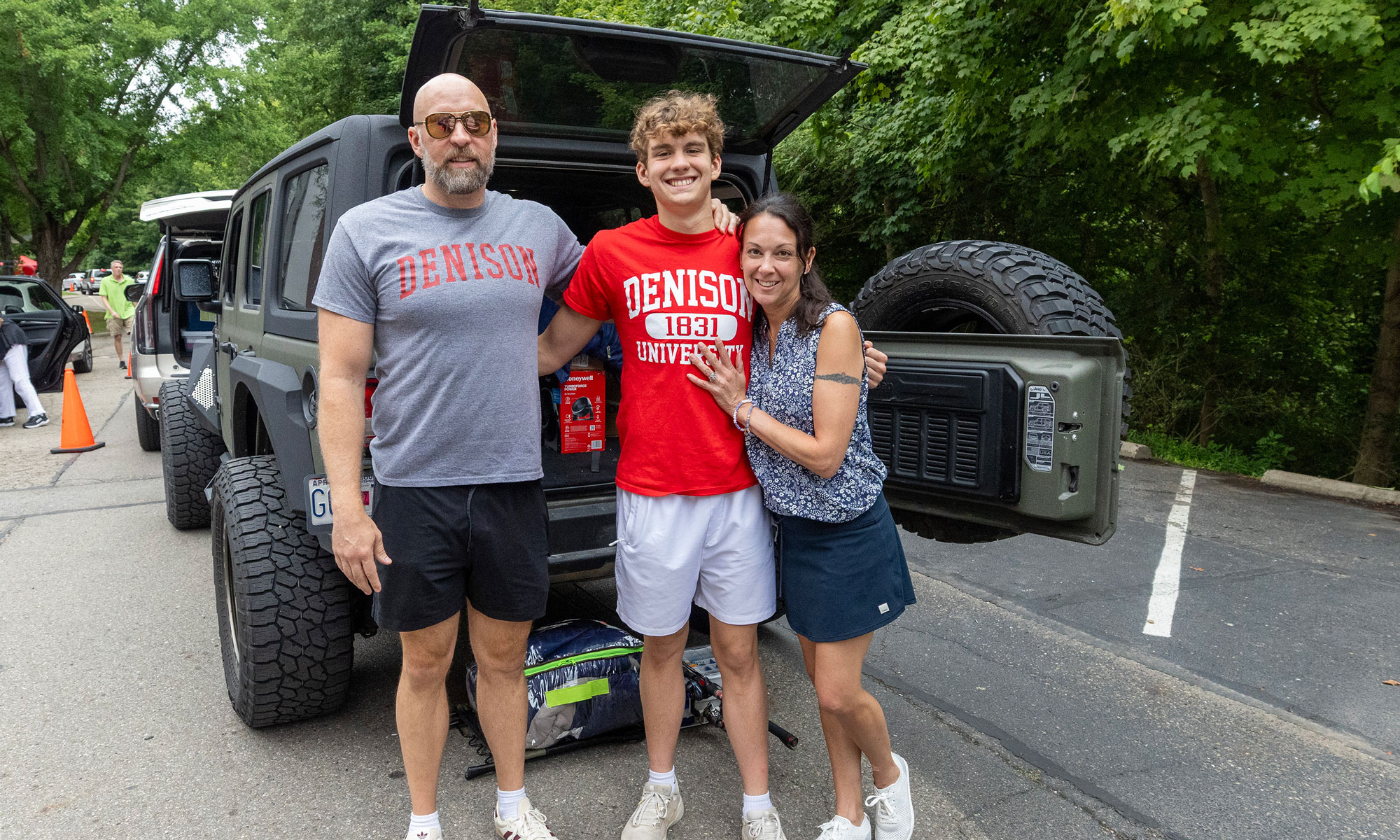 A famiily standing in behind a vehicle with an open door