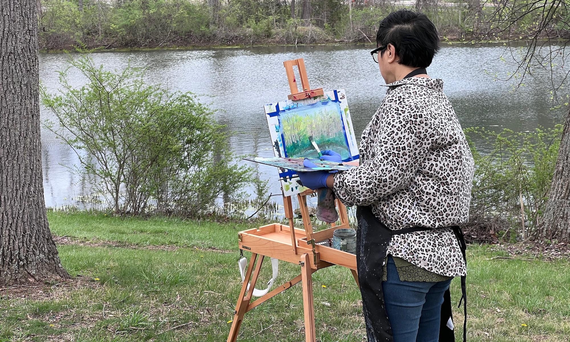 A student works on a painting overlooking Ebaugh Pond
