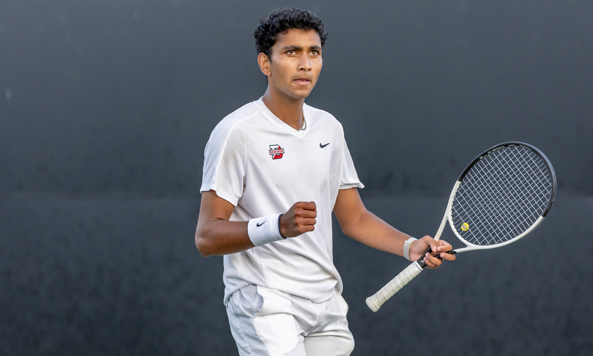 Photo of Kael Shah ’26 on the tennis court in his tennis uniform, holding a tennis racket.