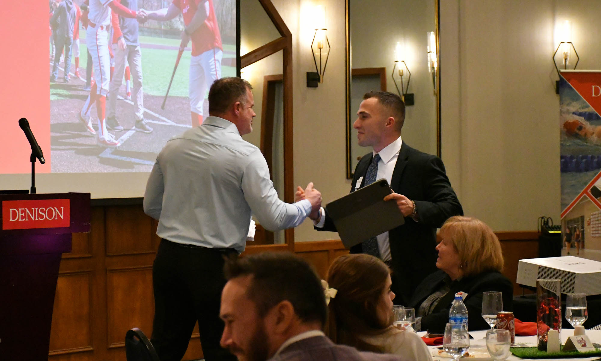 Denison coach Mike Deegan greets former Denison pitcher Matthew Zmuda at the First Pitch Banquet.