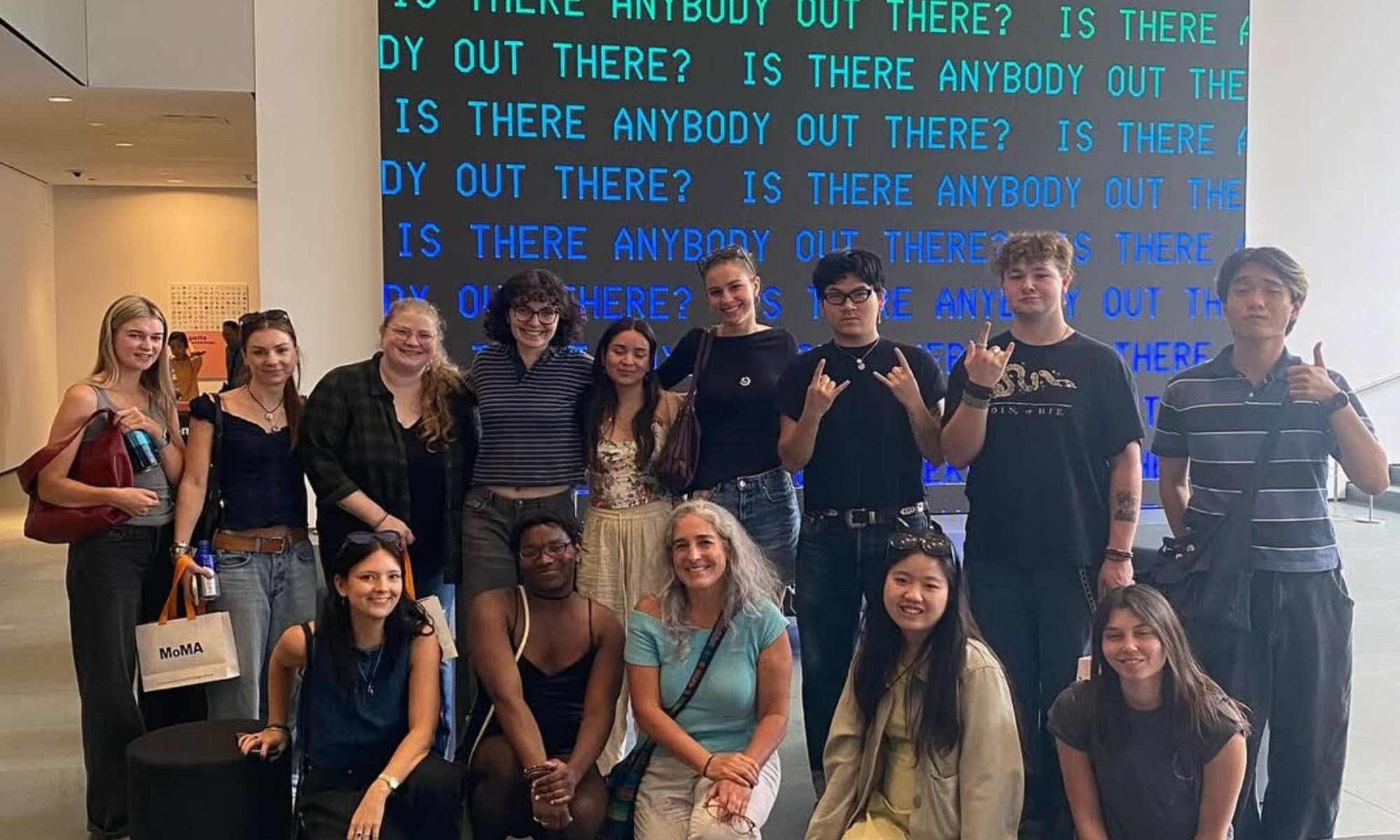A group of Denison students gather for a photo in front of an arts installation.