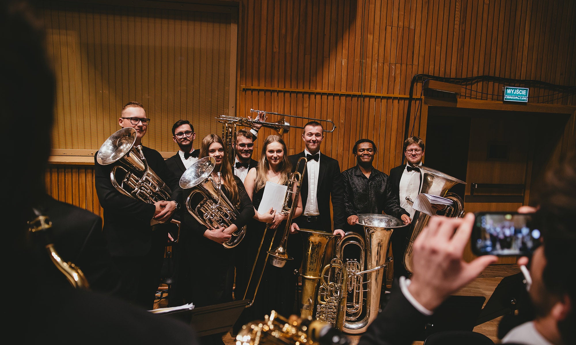 Musician pose for a group photo on a concert stage.