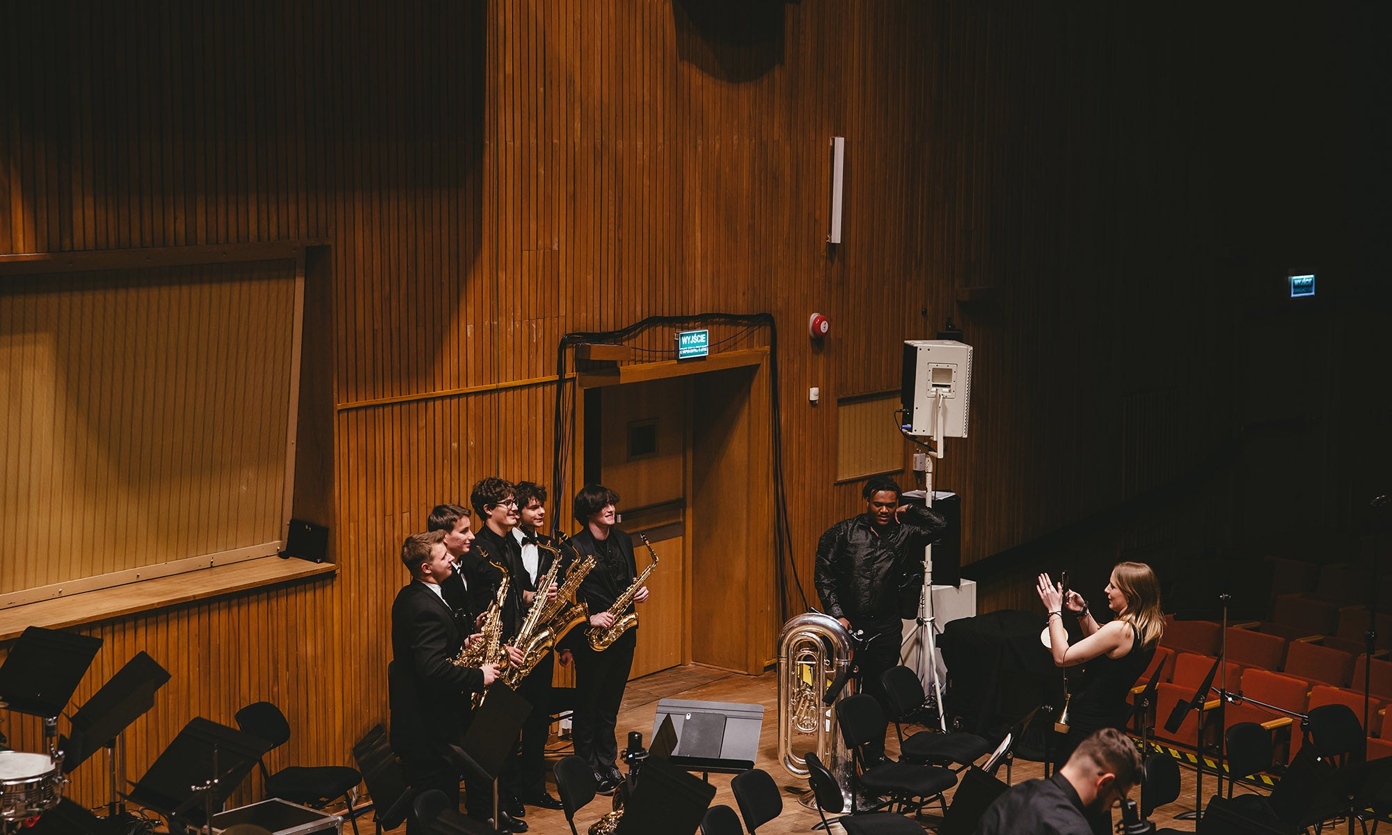 A view from the balcony of a concert stage where musicians are posing for photos.