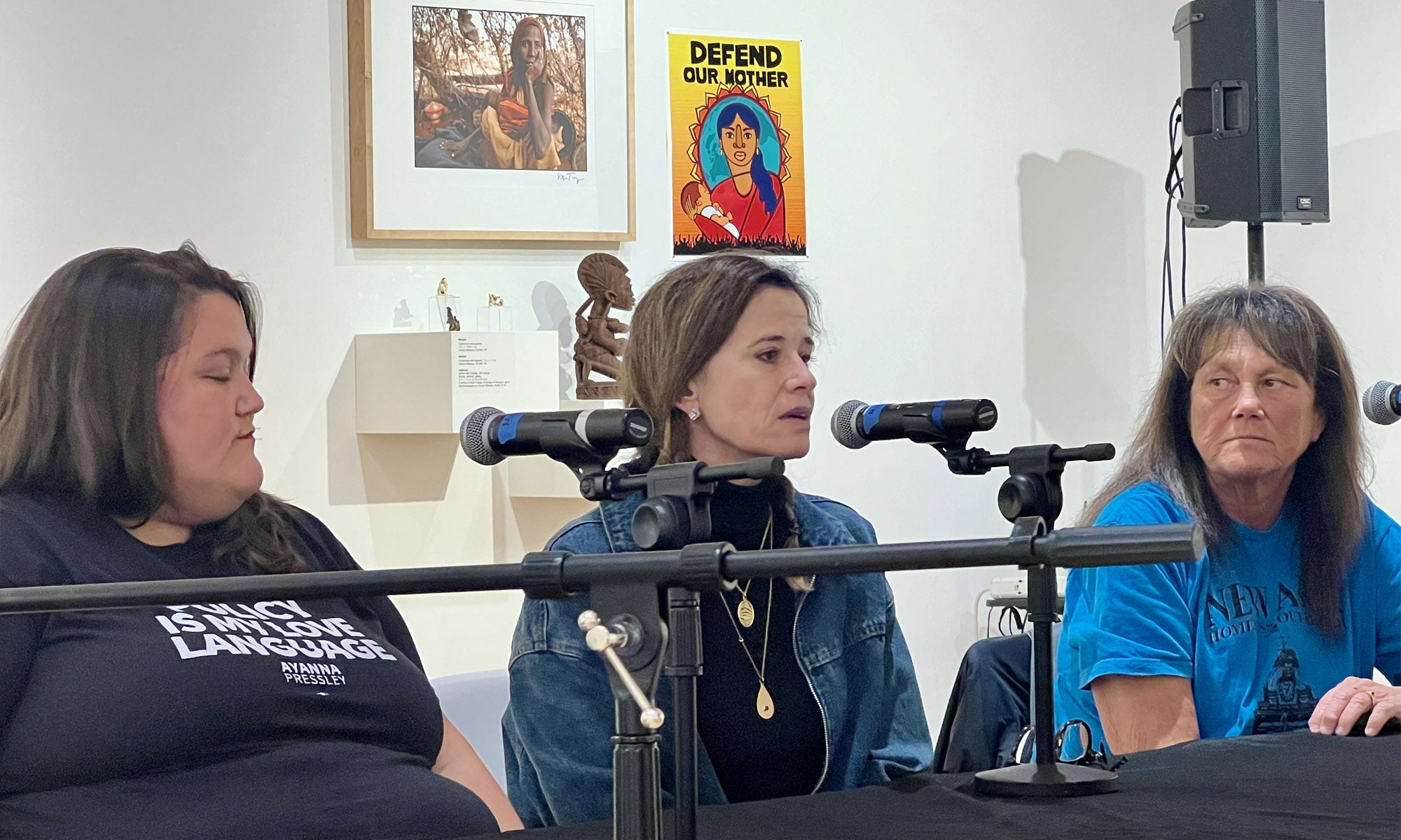 Three panelists sit at a table speaking into microphones.