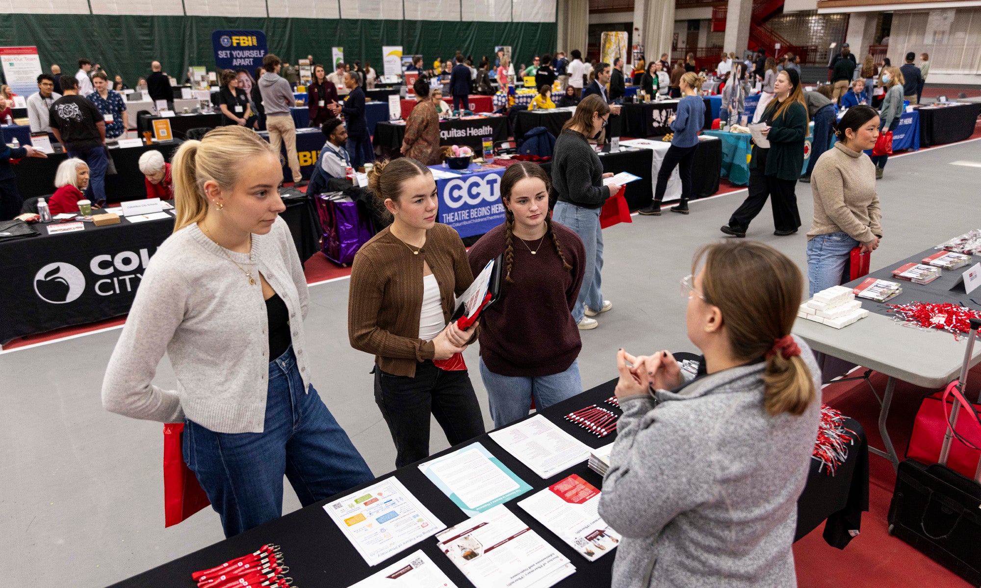 Three students talk to a career professional at a large career fair.