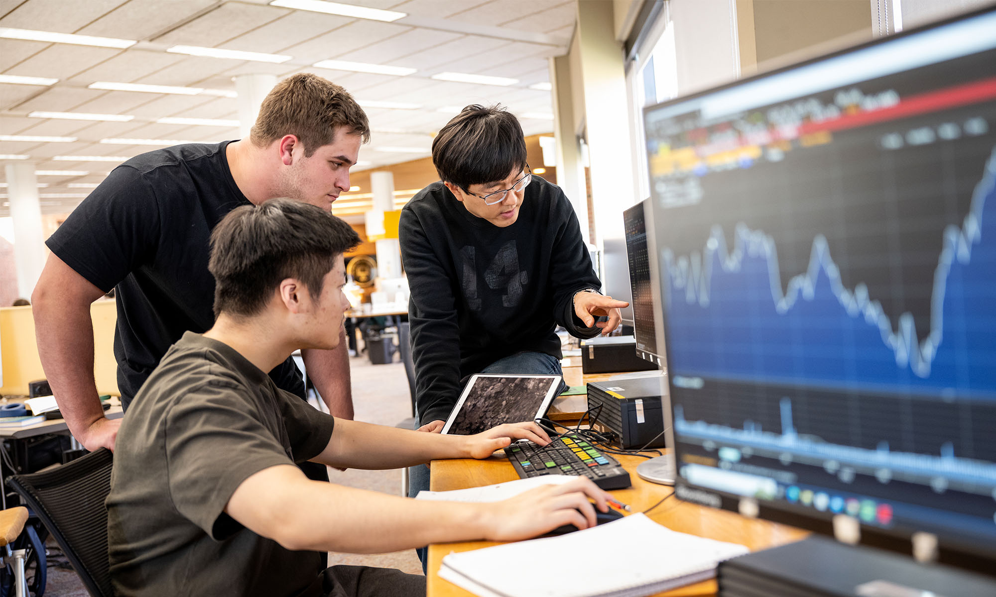 A teacher with two students reviewing data on a computer screen.