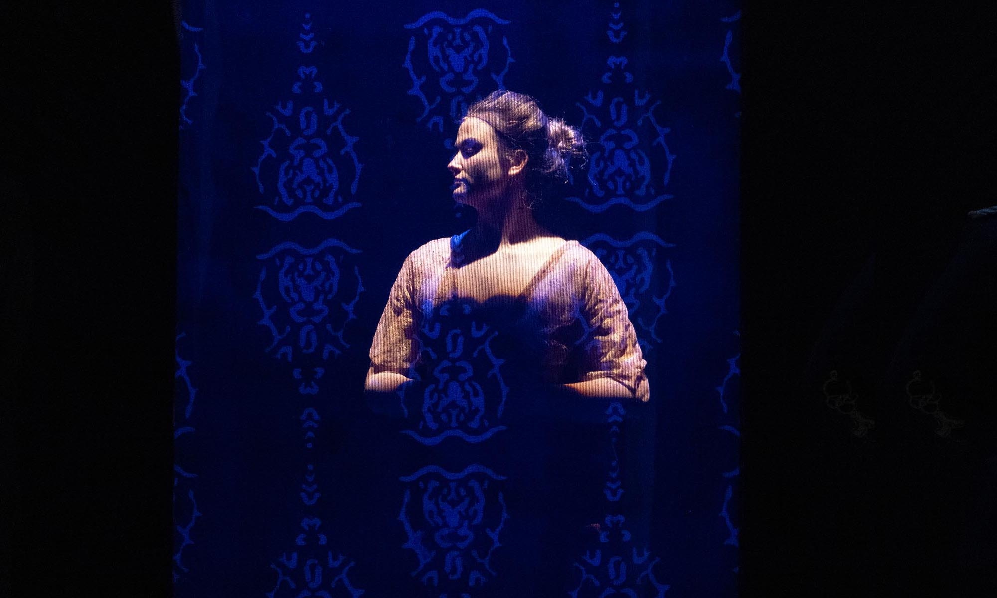 Denison Music Theatre student lit dramatically from above behind a lace scim.