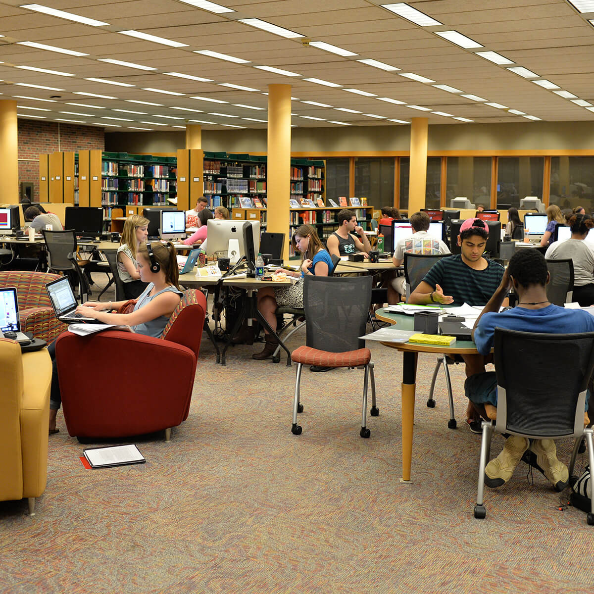 A large group of students studying and working in the library.